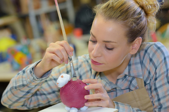 artist making and painting a clay sculpture