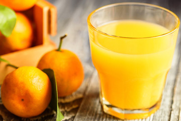 Glass of fresh juice and mandarins on table