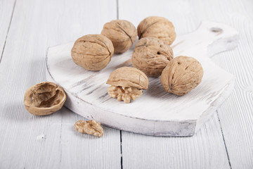 Walnuts on a white board on a white wooden table