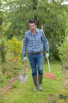 Gardener carrying spade and rake