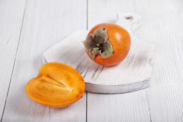 Persimmon on white board and part a persimmon beside
