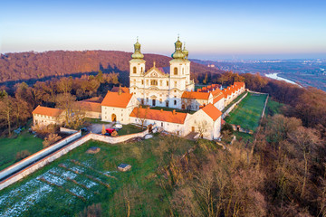 Camaldolese monastery and baroque church in the wood on the hill in Bielany, Krakow, Poland , Aerial view in sunset light with Vistula River and far view of Cracow city in the background