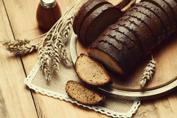 Sliced rye bread on a cutting board and wheat spikelets 