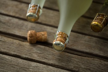 Bottles of champagne and its cork on wooden surface