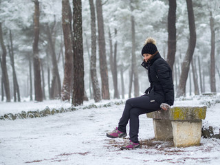 Mujer sentada en un banco de piedra meditando bajo la nieve