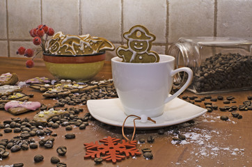 Christmas homemade gingerbreads with white frosting, coffee beans and rowan twig for decoration on a wooden board