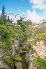 Fototapeta na wymiar A view to Guadalevin river at El Tajo Gorge Canyon and traditional andalusian houses at the cliff in Ronda, a famous white village (pueblo blanco) in Malaga province, Andalusia, Spain.