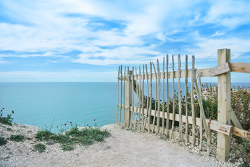 An old wooden fence at the edge of chalk cliffs, coastal erosion at Seven Sisters country park near...