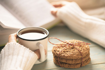Girl reading book and drinking tea in winter