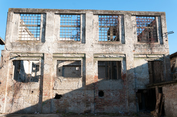 Old abandoned industrial factory warehouse building with brick wall broken windows and blue sky background