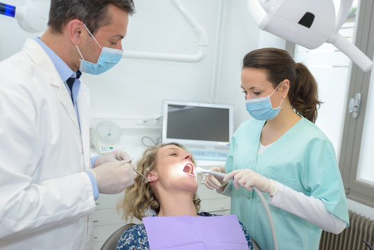 happy male dentist with assistant and female patient