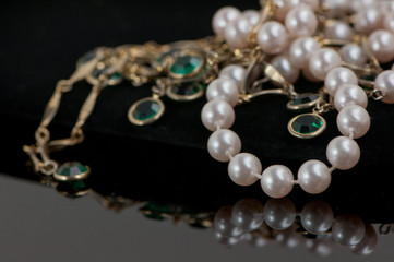 Pearls and emeralds on black background