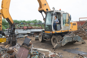 Woman using grabber in scrapyard