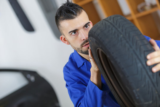 male mechanic checking a new car tyre