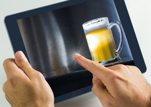 Hand touching tablet with beer in bar