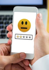 Hand holding phone with medium satisfaction smiley face and star