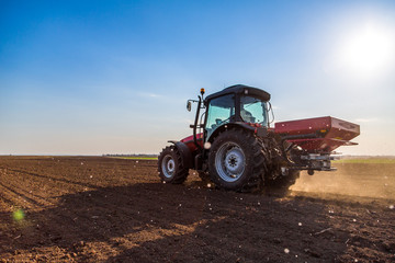 Farmer fertilizing arable land with nitrogen, phosphorus, potassium fertilizer