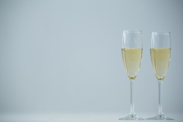 Two champagne flutes against white background