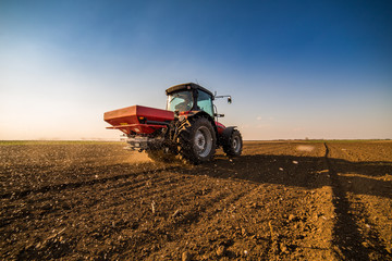 Obraz premium Farmer fertilizing arable land with nitrogen, phosphorus, potassium fertilizer