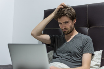 Jeune homme travaillant dans son lit