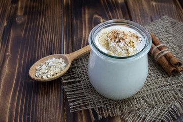 Milk yogurt with banana,oat flakes and cinnamon on the rustic wooden background