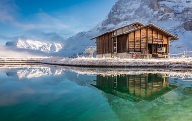 Hut and mountain peaks reflected in lake near Grindelwald, Switzerland.