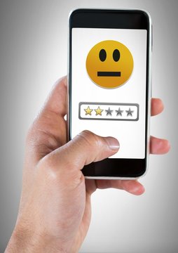 Hand holding phone with two star review medium rating smiley