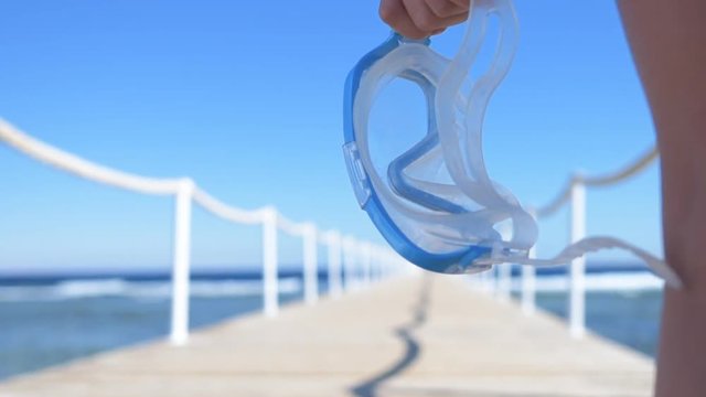 Woman's hand holds mask for diving . Pontoon bridge on the Red Sea. 