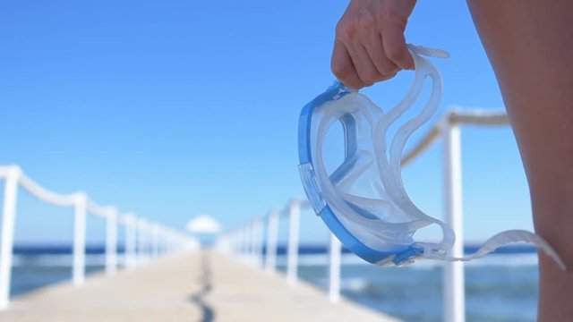 Woman's hand holds mask for diving . Pontoon bridge on the Red Sea. 