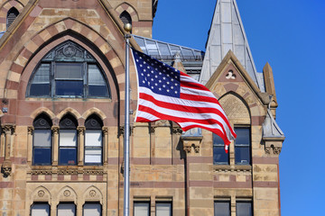 US National Flag in front of Syracuse Savings Bank Building at Clinton Square in downtown Syracuse, York State, USA.