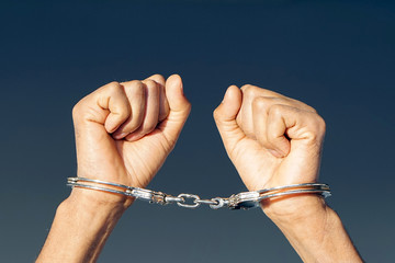 Close-up. Arrested man handcuffed hands at the back. Prisoner or arrested terrorist, close-up of...