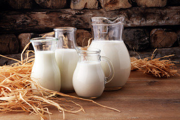 A jug of milk and glass of milk on a wooden table.