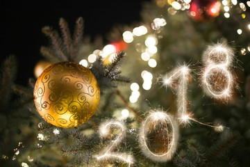 2018 sign written with sparkle firework on the Christmas tree background, happy new year 2018 concept.