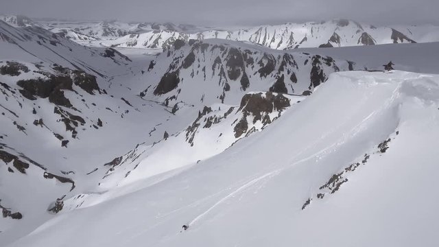 Aerial, people ski down smooth mountainside in Iceland