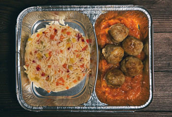 Healthy lunch in aluminum foil package. Top view. Lunch box with food ready to go for work or school. Potatoes and chicken mea