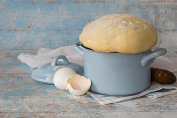 Special yeast dough for making homemade pies and buns in a small saucepan on a wooden background. Selective focus.