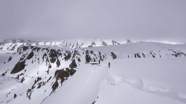 Skiers on top of snowy mountain in Iceland, aerial