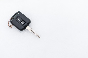 A black car key lies on the snow.