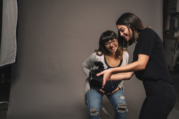 Pregnant woman doing a photoshoot with a female photographer in a studio