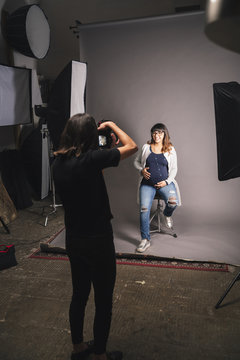 Pregnant woman doing a photoshoot with a female photographer in a studio