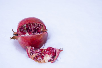 The pomegranate is red, mature, lying sideways on the snow. Individual share