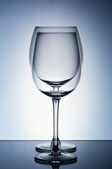 Two empty wineglass for red wine on diffusion lit background in abstract .. composition with reflection