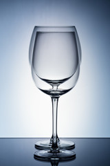 Two empty wineglass for red wine on diffusion lit background in abstract .. composition with reflection