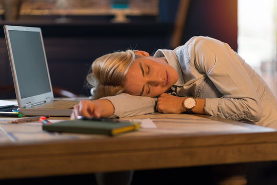 Young exhausted woman sleeping at the table in the office. - Powered by Adobe