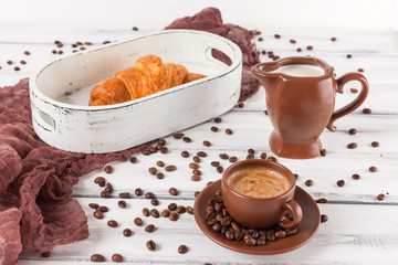 Freshly baked croissants on brown napkin, cream, to cups of coffee in ceramic dishes on white wooden background. Fresh pastries for breakfast. Delicious dessert. Closeup photography.Horizontal banner