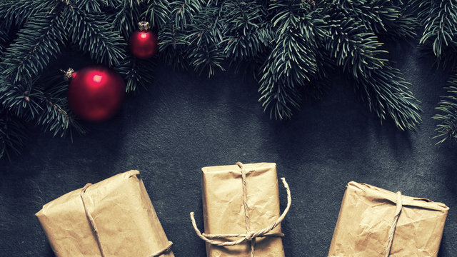 Gift boxes and christmas fir tree with christmas red balls on a black background. Christmas background