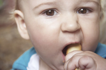 Cute baby with an appetite is eating a bagel