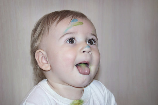Cute child with painted face looking upward and showing tongue
