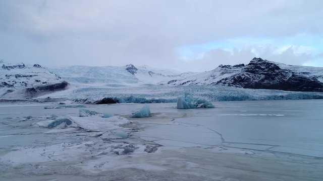 Aerial footage of blue icebergs in frozen lagoon, Fjallsárlón Iceland