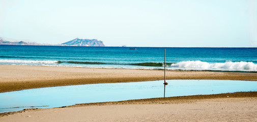 Vista de la playa de San Juan en Alicante, España con el fondo de la ciudad de Benidorm una mañana soleada y tranquila  de invierno sin nubes y con temperatura templada y ambiente apacible y relajante